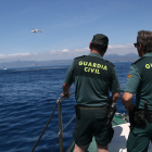 Dos agents de la Guàrdia Civil observen com l'helicòpter de Salvament Marítim maniobra en un simulacre a la costa de Cambrils.