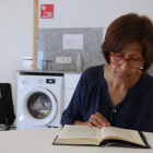 Isabel García, una usuària de Càritas, llegint un llibre mentre espera que acabi la rentadora en un dels punts amb serveis comunitaris de l'entitat
