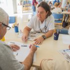 Una membre de l’equip tècnic del programa d’estimulació cognitiva de l’Hospital de Dia Francolí atén a dos usuaris.