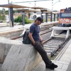 Un usuari capcot espera el tren a l'estació de Sant Vicenç de Calders