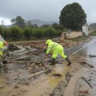 Uns operaris netejant la carretera d'accés a Manuel tallada per la DANA.