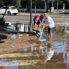 Dos veïns treuen aigua del carrer Josep Vicenç Foix de Sitges, anegat per la tempesta.