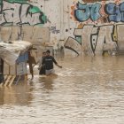 Dues persones travessen un terreny de barraques inundat al costat de la V-30 a causa de les pluges torrencials de les últimes hores.