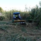 Un tractor treballant en la neteja de la riera de Maspujols.