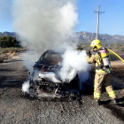 Un membre del cos de Bombers treballa en l'extinció de les flames d'un vehicle en una zona propera a la N-340 a l'Ametlla de Mar.