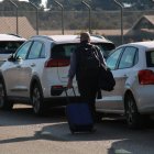 Un home amb una maleta caminant pels vorals de l'entrada de l'estació del Camp de Tarragona després d'aparcar-hi el seu vehicle.