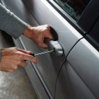 Imatge d'un lladre intentant forçar la porta d'un cotxe amb un tornavís.
