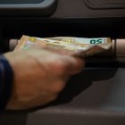 Una persona que retira diners d'un caixer automàtic