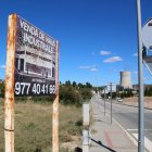 Antic cartell de venda de naus industrials davant dle tancat on es construeixen les noves infraestructures