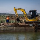Un operari treballant amb una màquina excavadora al canal dret de l'Ebre després dels aiguats