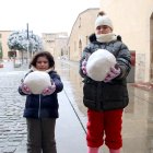 Dos nens mostren les boles de neu que han fet al monestir de Poblet.