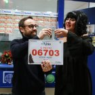 Dos trabajadores de la administración Doña Pilar de Salou brindando con cava y mostrando el cartel del primer premio del Sorteo del Niño.