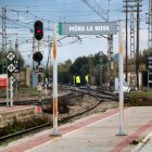 Cartells a l'estació de tren de l'R-15 a Móra la Nova, amb dos operaris al fons fent comprovacions a les vies