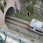 Vista des d'un talús d'un tren de l'R1 entrant en un túnel en un tram on hi ha circuació per via única