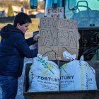 Un noi col·loca el cartell de 'Revolta pagesa' en un tractor.