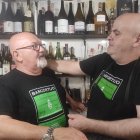 Dos homes mirant-se davant de prestatgeries plenes de vi