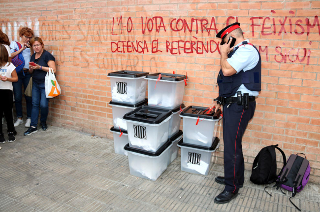 Un agents dels Mossos inspeccionant unes urnes requisades l'1 d'octubre passat.