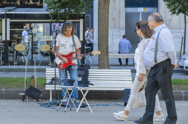 Imatge d'un músic de carrer tocant la guitarra i cantant a la Rambla Nova de Tarragona.
