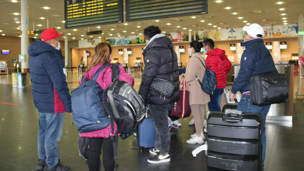 Un grup de passatgers miren el tauler de sortides de l'aeroport de Reus.