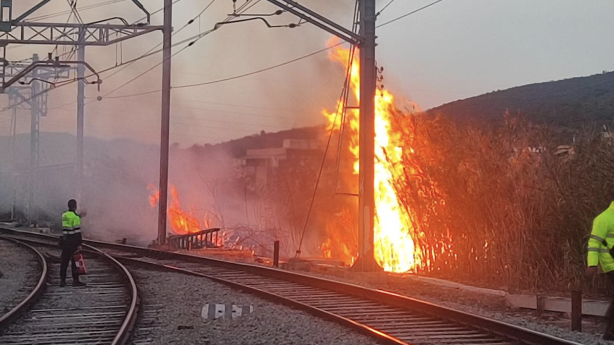 Un fuego quema al lado de líneas de tensión.