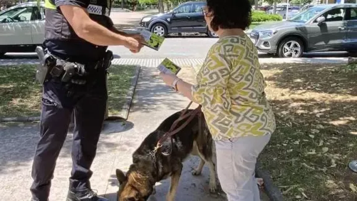 Un agente de la Policía Local de Salou entrega una tarjeta informativa a una mujer que pasea su perro