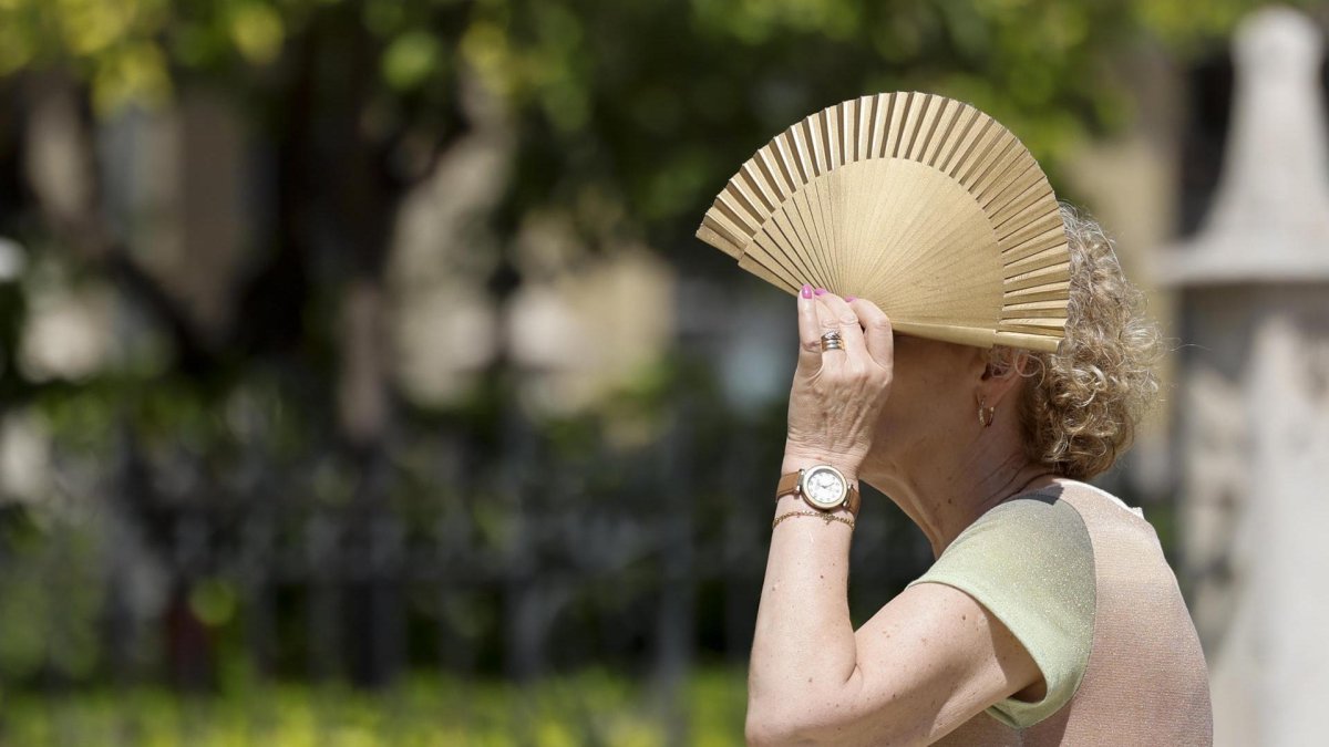 Una mujer se protege del sol con un abanico.