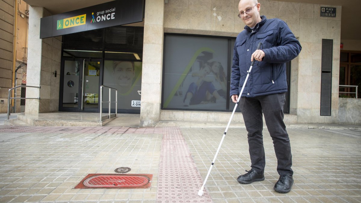 El director de la ONCE en Reus, Fran Sánchez, mostrando el pavimento podotáctil delante de la sede de la entidad en la plaza de la Llibertat.
