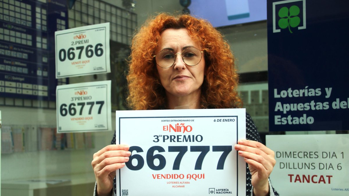 La responsable de la administración de Alcanar, Mònica Alvaredo, sujetando el cartel del tercer premio de la rifa de Reyes después de vender un décimo.