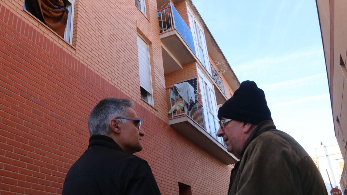 Marcel·lí Balcells, propietario de un piso de un bloque ocupado de Santa Bárbara de donde se ha tenido que marchar, acompañado de un amigo delante del edificio ocupado