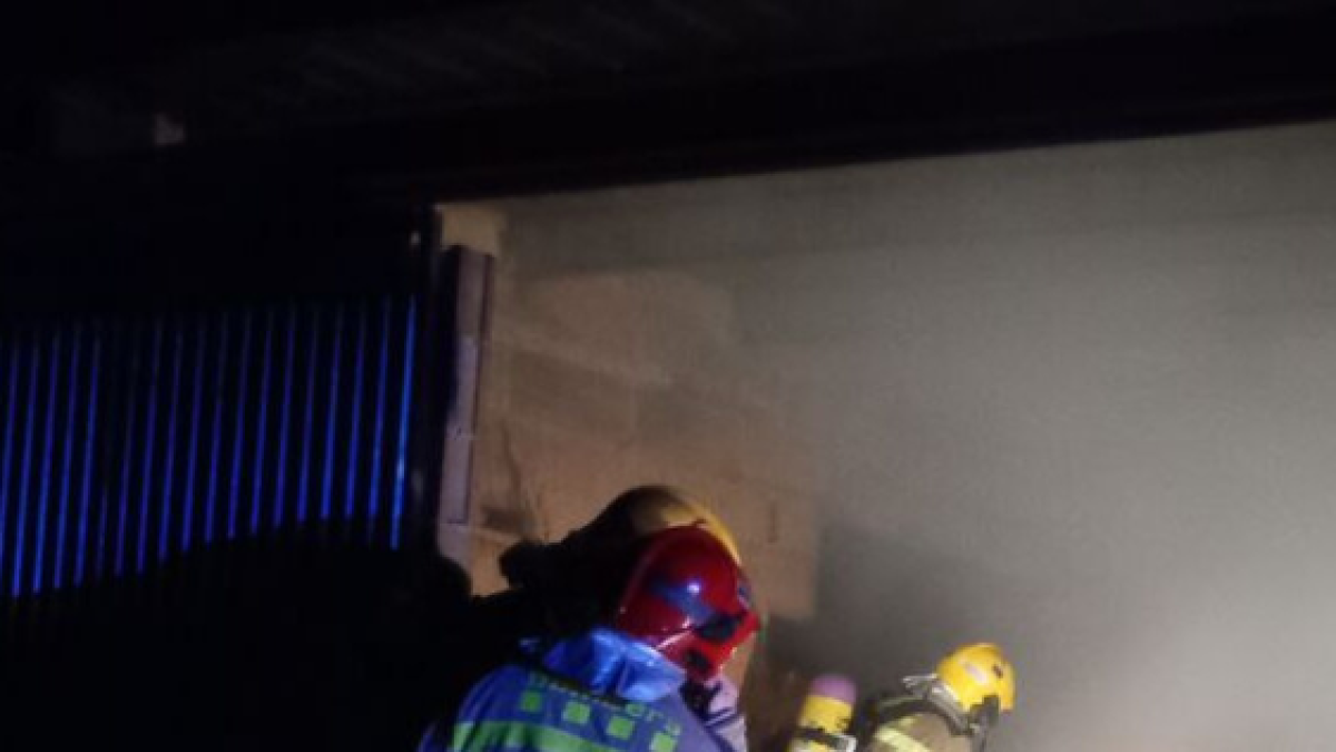 Els bombers remullant el paller de Mas de Barberans incendiat.