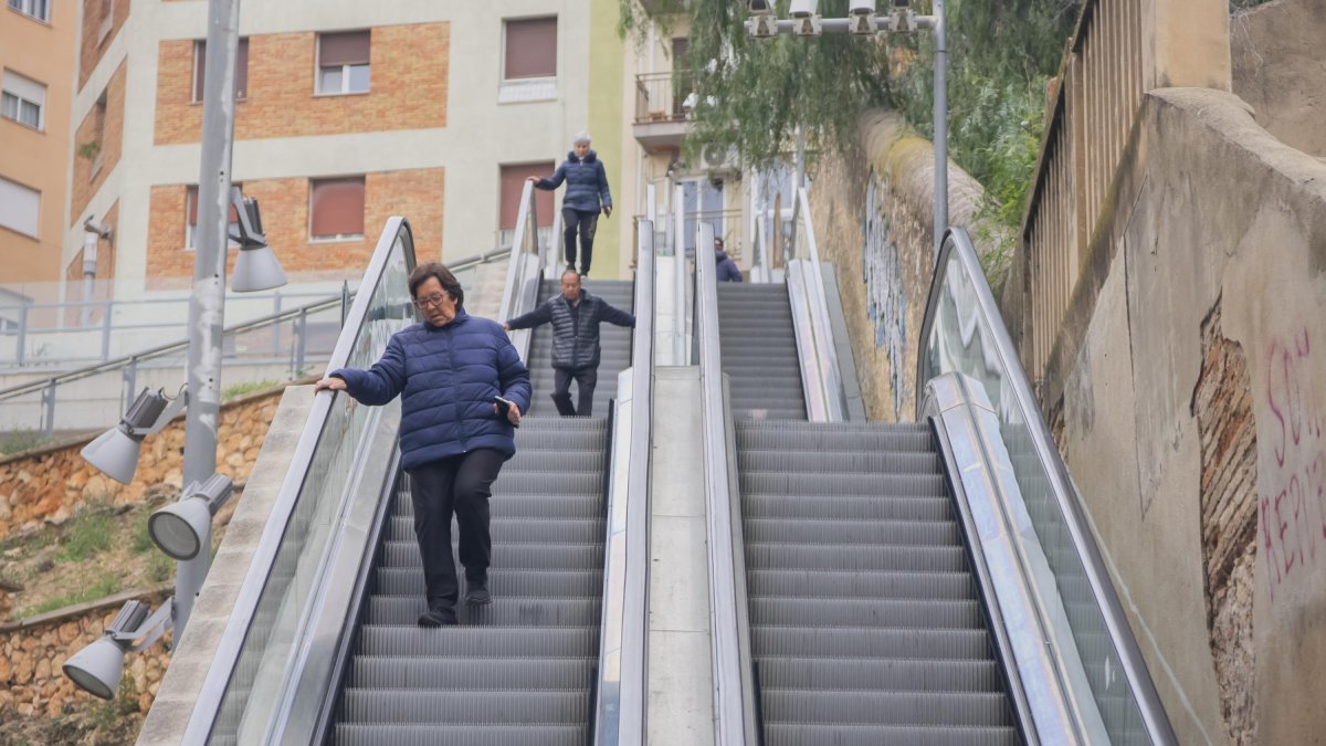 Usuaris de les escales mecàniques del carrer Vapor, baixant els graons a peu.