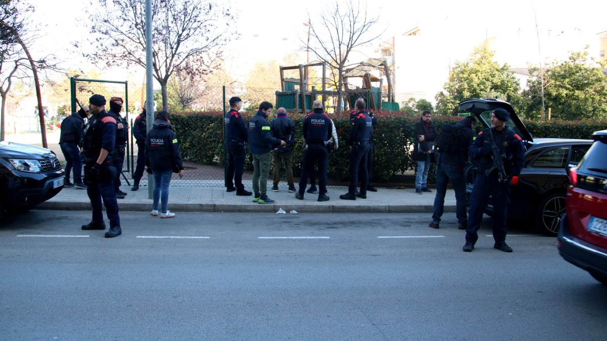Agentes de los Mossos d'Esquadra y de la Guardia Civil custodiando a dos detenidos en el cacheo hecho en dos vehículos en el marco del operativo policial contra un grupo investigado por tráfico de drogas y falsificación de moneda.