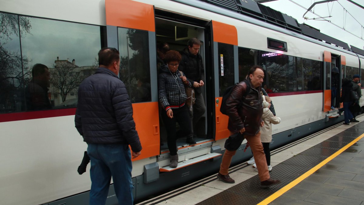 Usuaris baixant i agafant un tren de l'R2 Sud arribant a l'estació de Calafell.