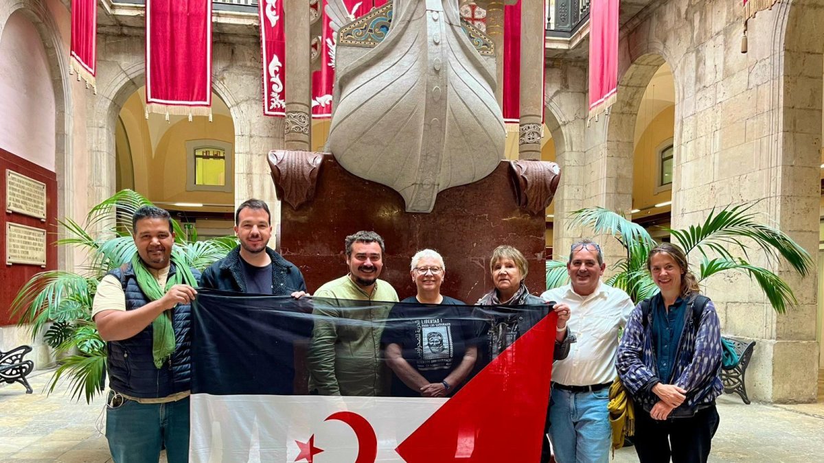 Imagen de representantes de ECP Tarragona, la activista Claude Mangin y otros participantes de la marcha internacional en el patio Jaume I del Ayuntamiento de Tarragona con una bandera de la República Árabe Saharaui Democrática.