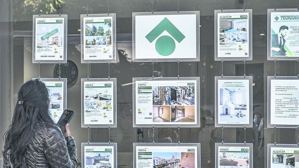 Una dona mira els anuncis d’habitatges exposats en una immobiliària.