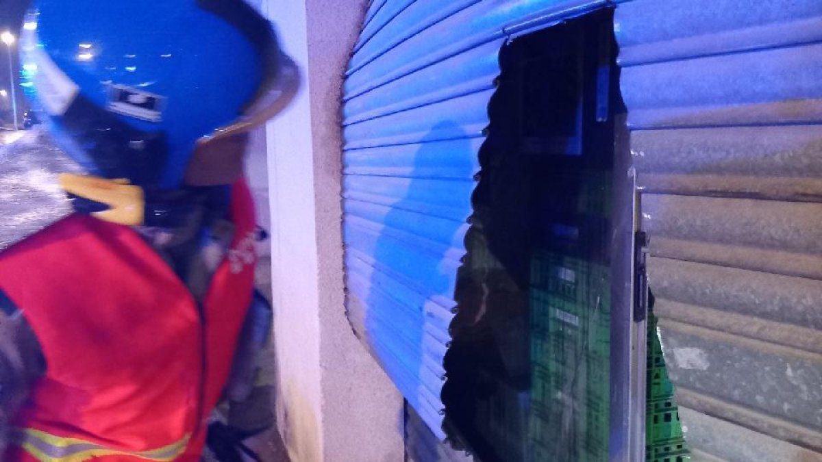 Els bombers van haver de tallar la persiana per poder accedir al local.