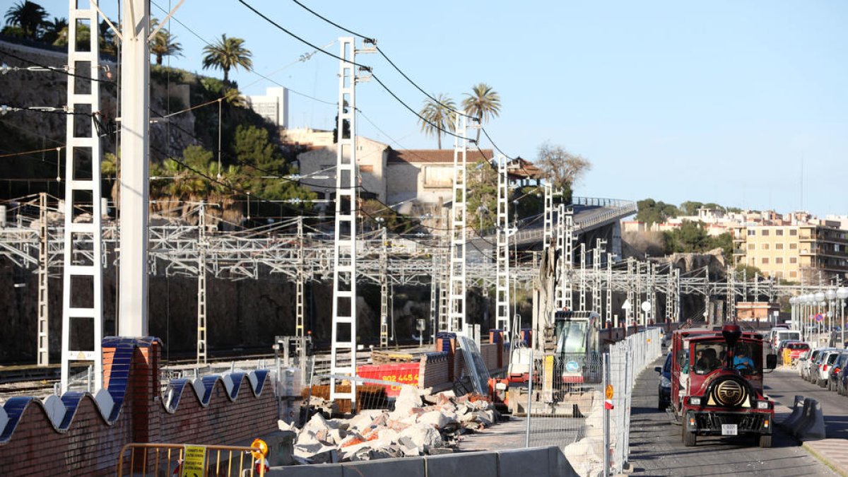 Les màquines enderroquen el mur que separa les vies del tren amb el passeig