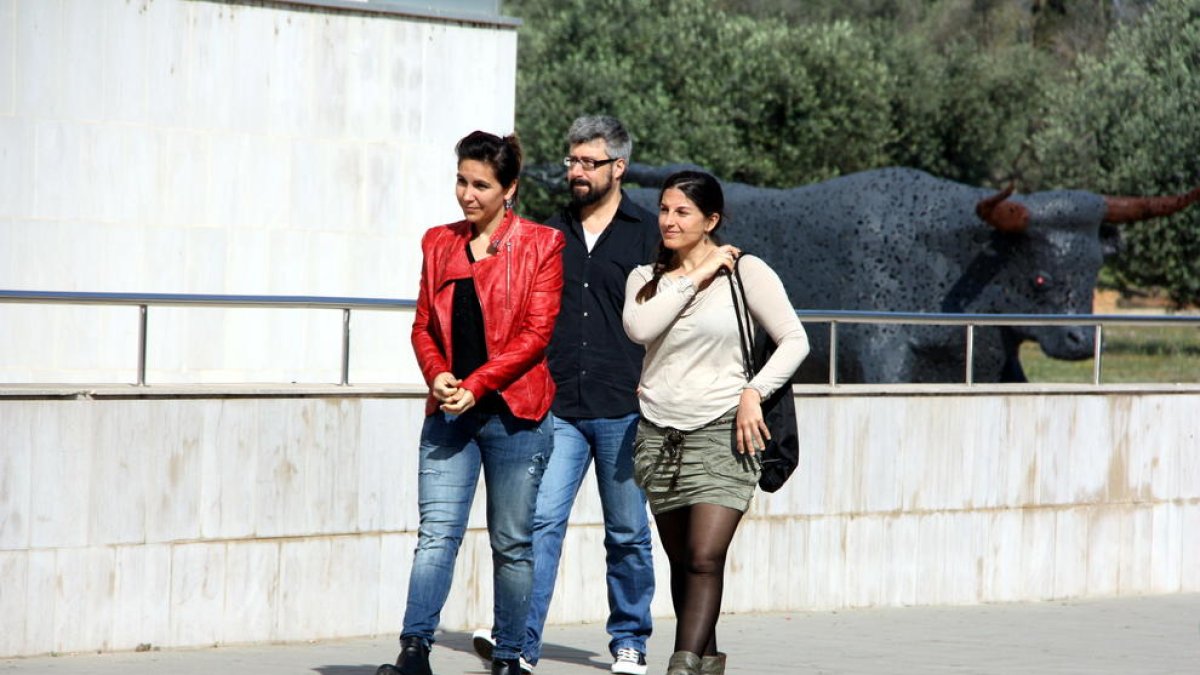 Les dues activistes d'AnimaNaturalis, Aïda Gascón i Yasmina Moreno, que van ser agredides al Mas de Barberans, arribant amb un company als jutjats d'Amposta, amb el gran bou que presideix una rotonda d'Amposta al darrera. Imatge 17 de maig de 2015. (Horit