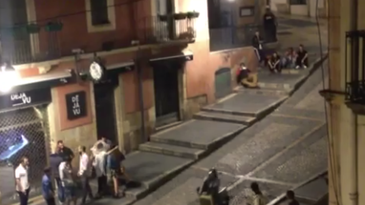 Uns joves recorren sobre uns contenidors la Baixada Misericòrdia en plena matinada