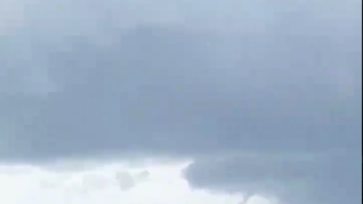 Un pescador grava dos mangueras dentro del mar en Cambrils