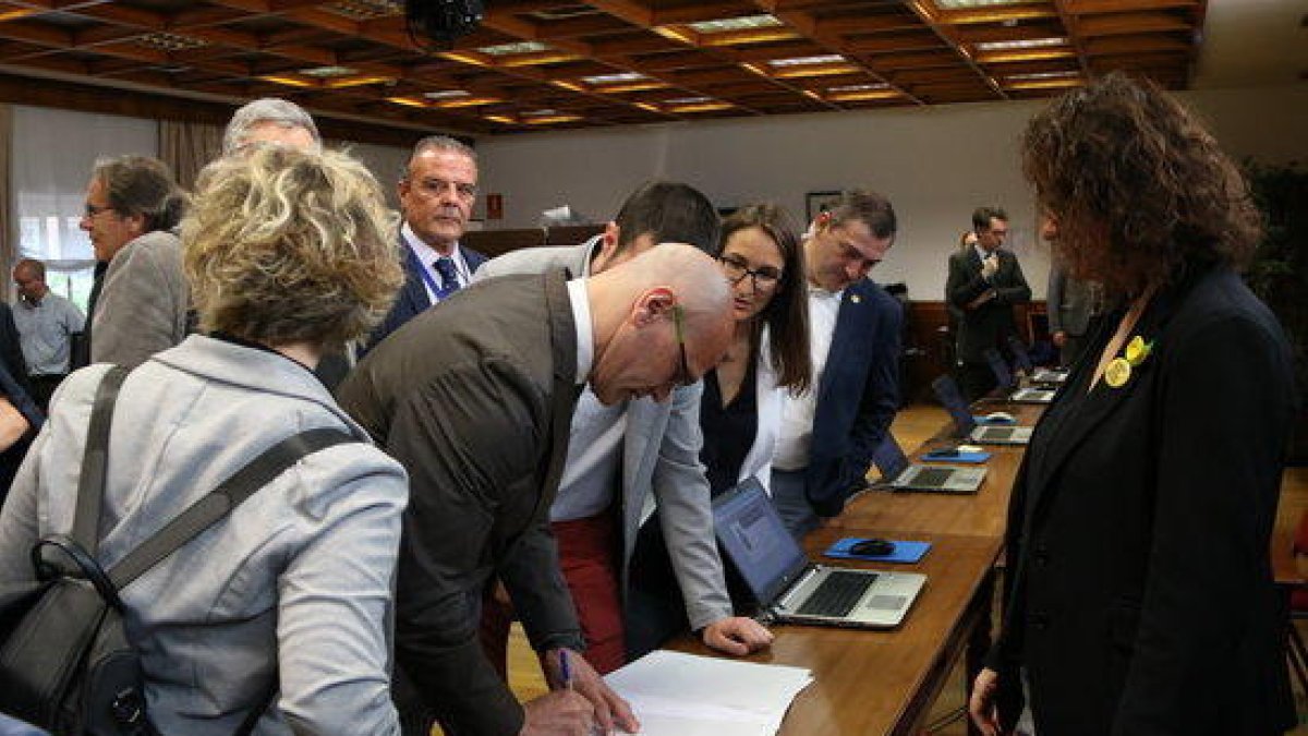 El senador electe d'ERC Raül Romeva signant un document durant el tràmit de recollida de l'acta de senador acompanyat d'altres senadors republicans.