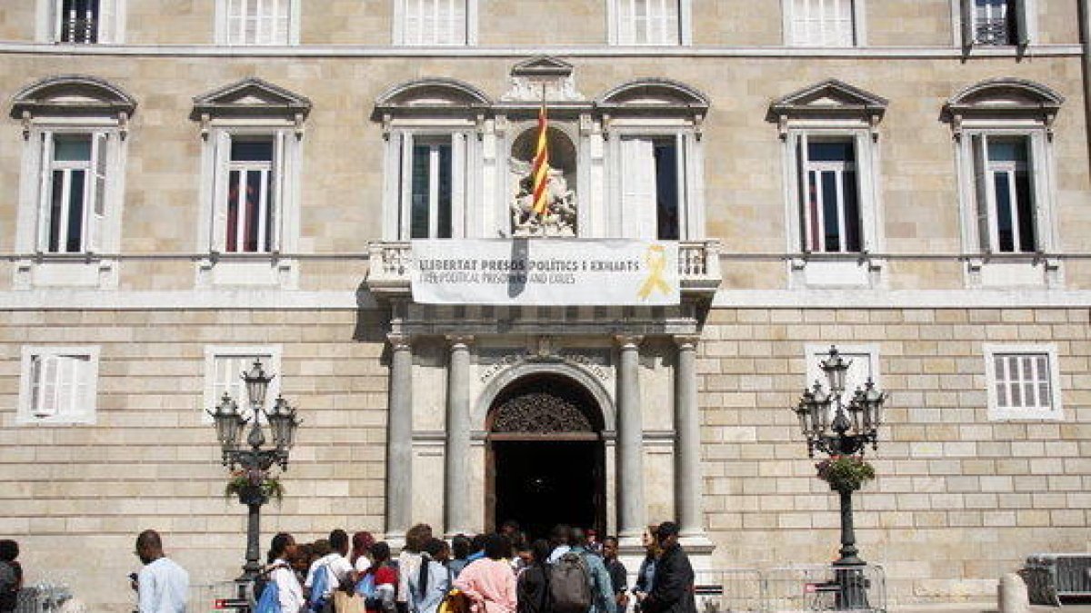 La fachada del Palau de la Generalitat con la pancarta restablecida y un grupo de personas mirando la fachada este 27 de mayo.