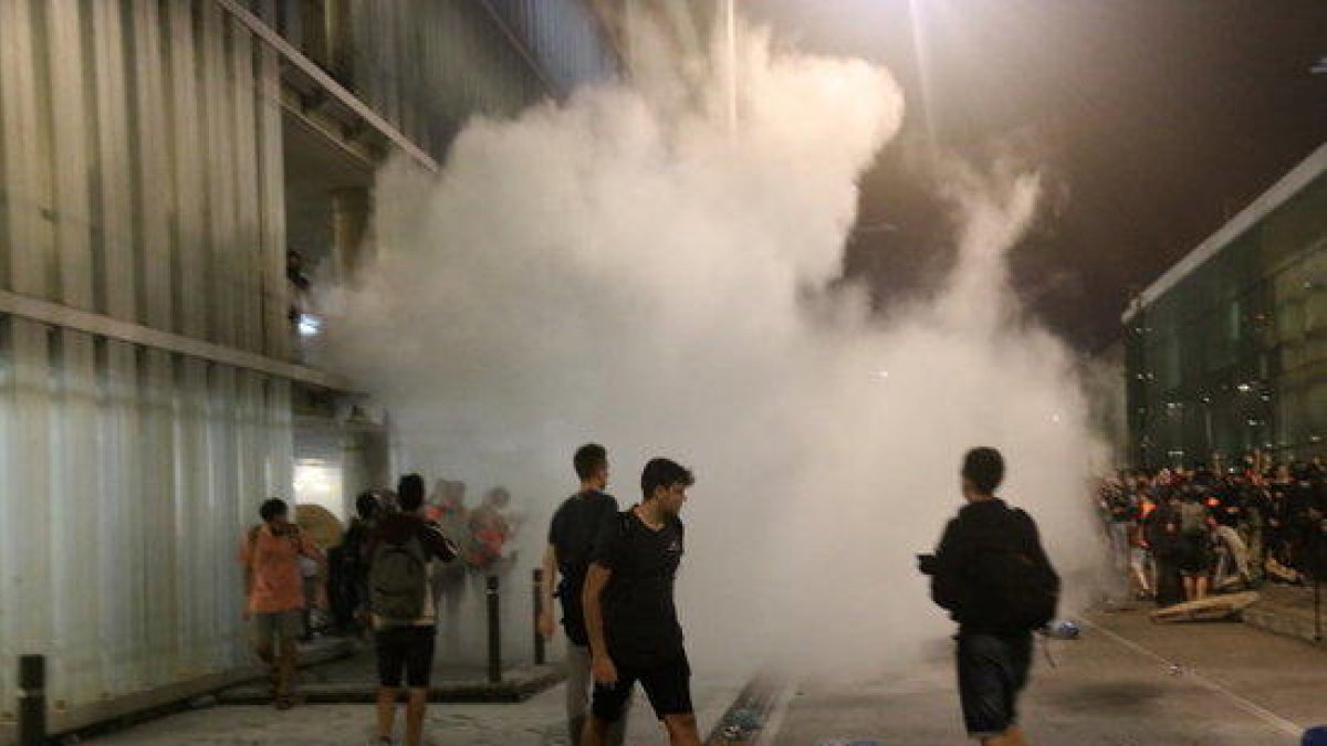 Un grup de manifestants a l'aeroport del Prat convocats per Tsunami Democràtic, enmig de fum.