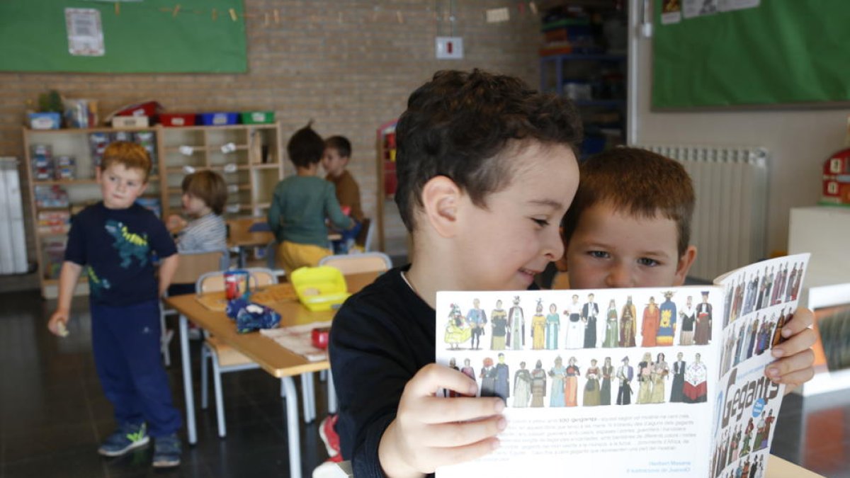 Unos niños mirando un libro de gigantes en la escuela Corazón|Coro de Roble de Santa Coloma de Queralt.