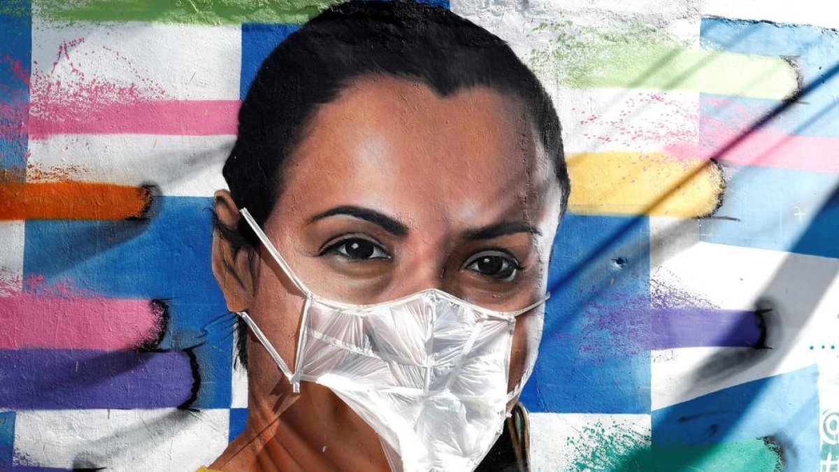 Un artista posa màscares a grafitis per a alertar de la COVID-19 al Brasil