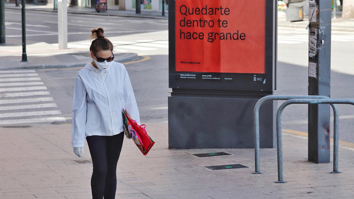 Una dona amb mascareta caminant perl carrer.