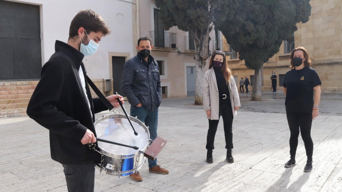 Plan|Plano general de un miembro de la banda|lado del paso La Flagel·lació de la Real y Venerable Congregación de la Puríssima Sang tocando el timbal y de representantes de otras cofradías de Tarragona. Imagen del 1 de abril del 2021 (Horizontal).