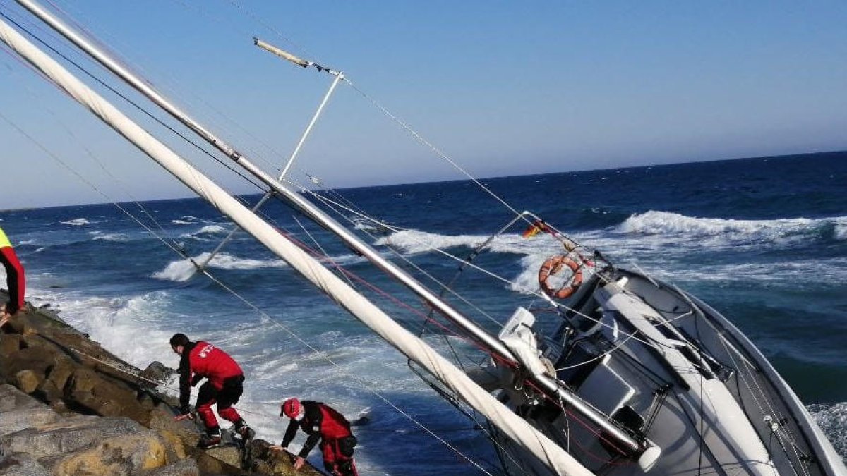 Los Bomberos rescatan a tres personas del interior de un velero atrapado en unas rocas