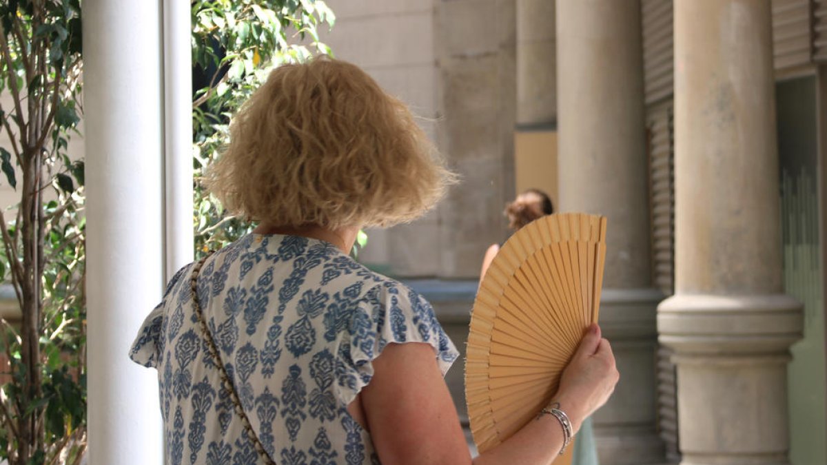 Una mujer se abanica con un abanico para combatir el calor