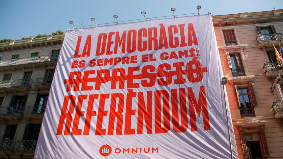 Òmnium despliega una pancarta en el centro de Barcelona reclamando un referéndum al Estado